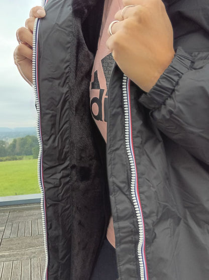 Black Laura Jo raincoat with faux fur lining and tricolor zip, shown open outdoors
