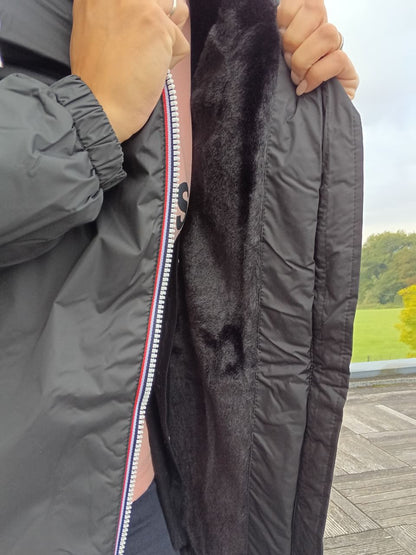 Black Laura Jo raincoat with faux fur lining and tricolor zipper, shown open outdoors