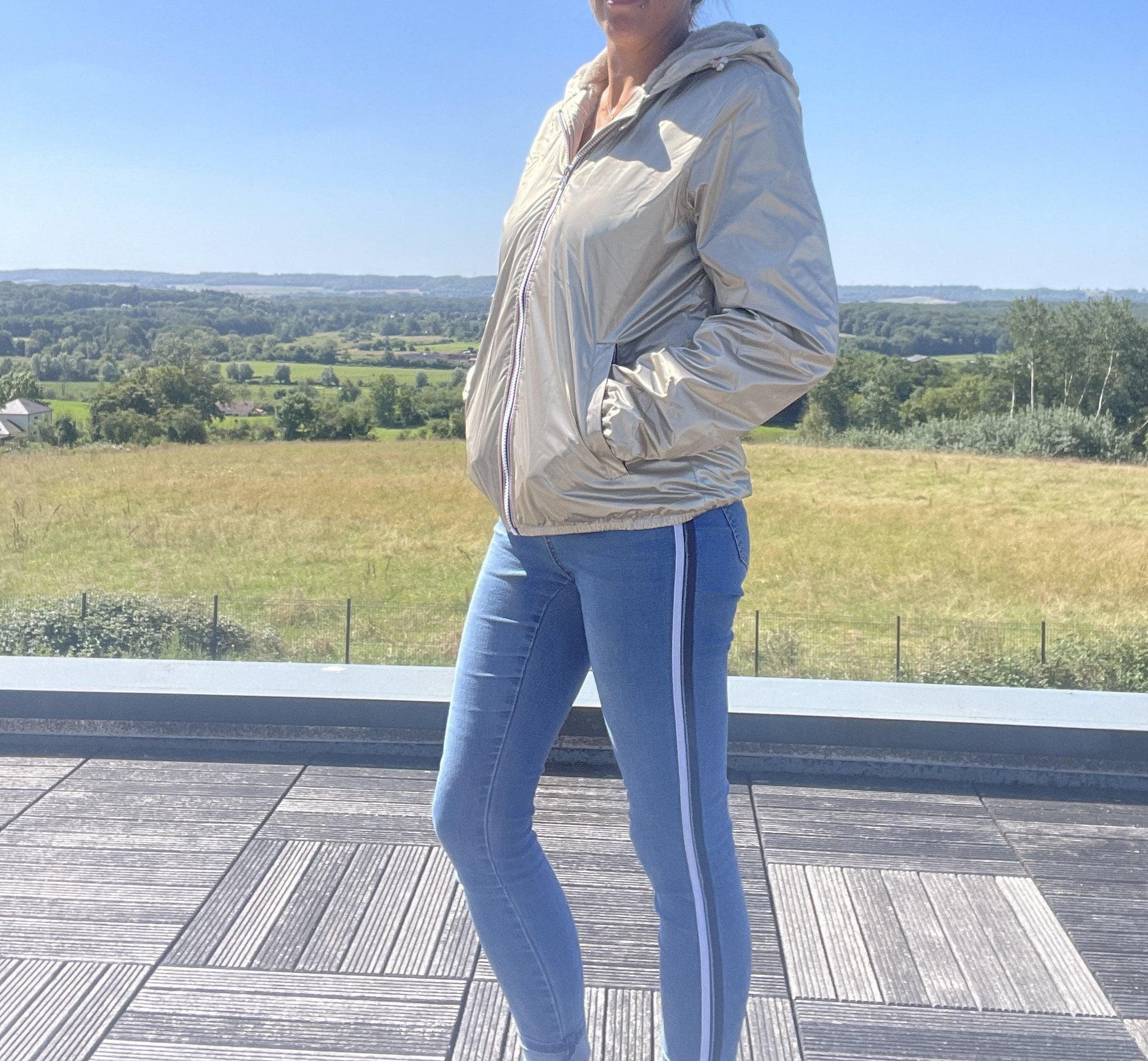 Woman wearing Laura Jo gold short waterproof jacket and jeans outdoors, Le Petit Placard
