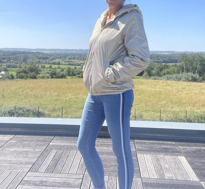 Woman wearing Laura Jo gold short waterproof jacket and jeans outdoors, Le Petit Placard
