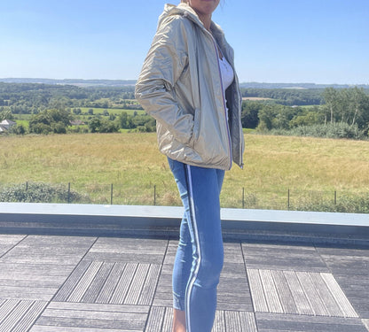 Woman wearing Laura Jo gold short waterproof jacket and blue jeans outdoors, Le Petit Placard