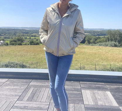 Woman wearing gold Laura Jo short waterproof jacket and blue jeans outdoors at Le Petit Placard