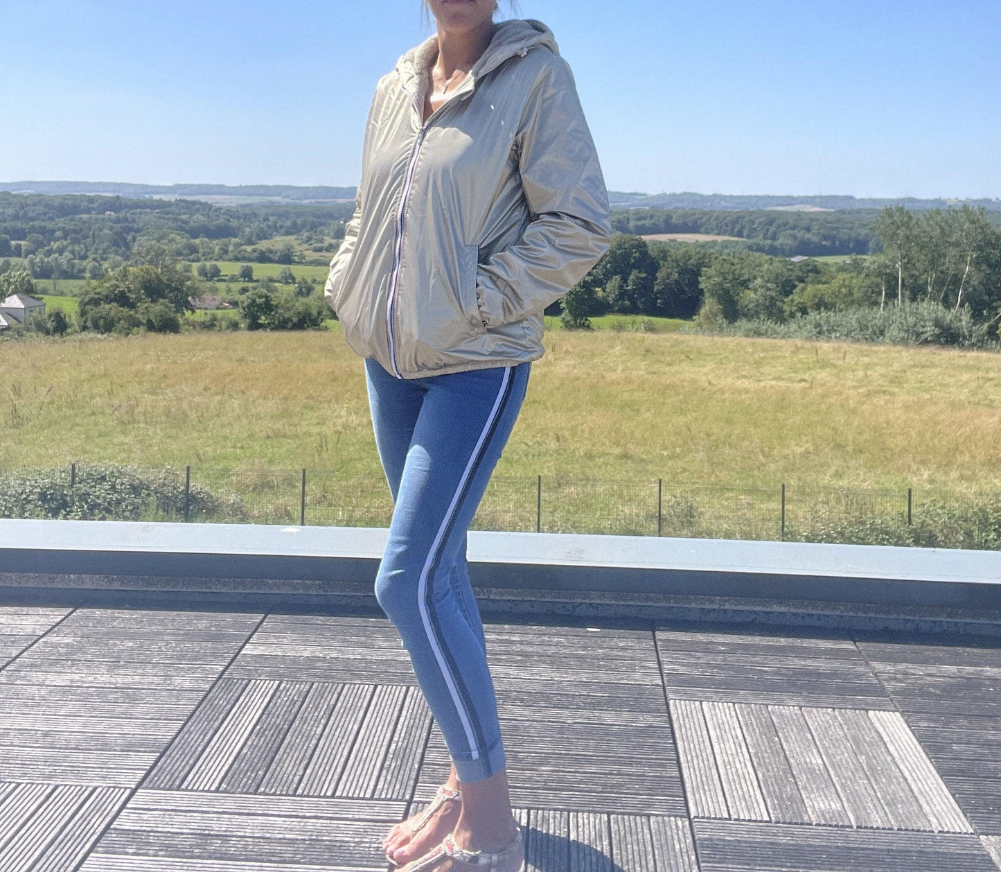 Woman wearing a gold Laura Jo short waterproof jacket outdoors, modern casual style