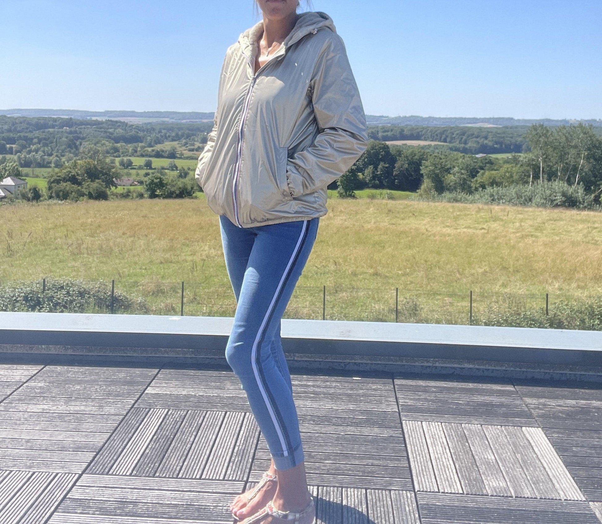 Woman wearing a gold Laura Jo short waterproof jacket outdoors, modern casual style