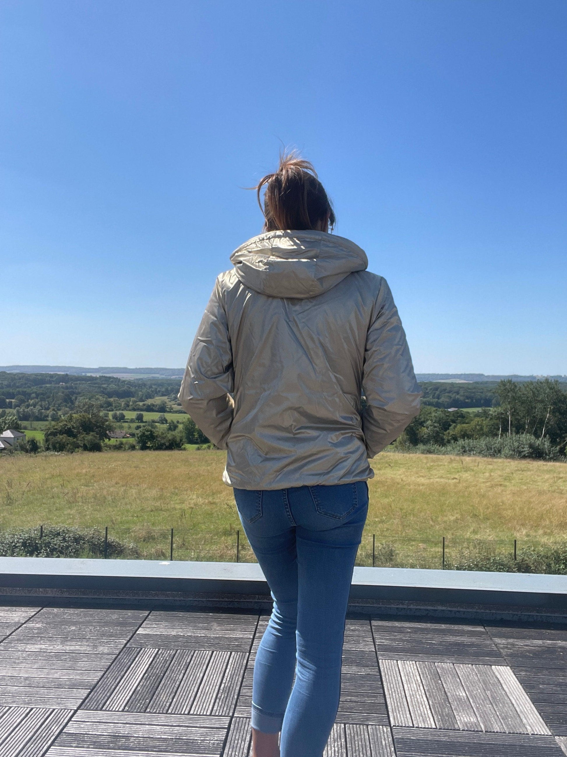 Woman wearing a short gold Laura Jo waterproof jacket outdoors, Le Petit Placard