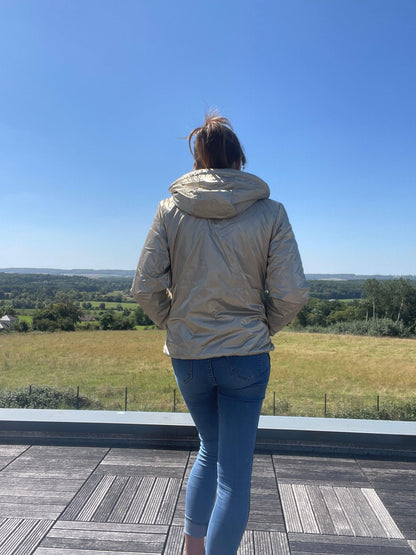 Woman wearing a short gold Laura Jo waterproof jacket outdoors, Le Petit Placard