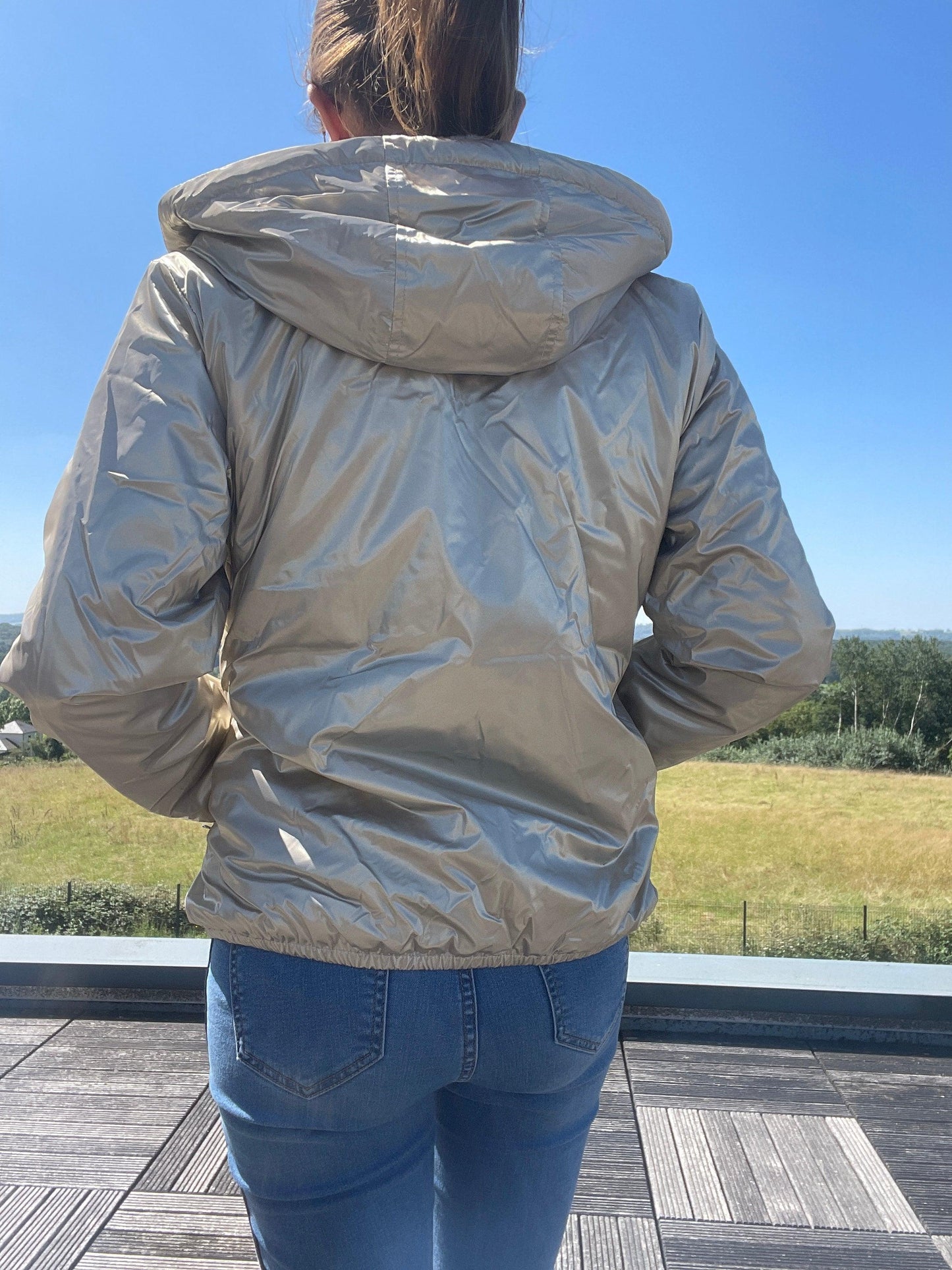 Woman outdoors wearing Laura Jo short gold waterproof jacket from Le Petit Placard