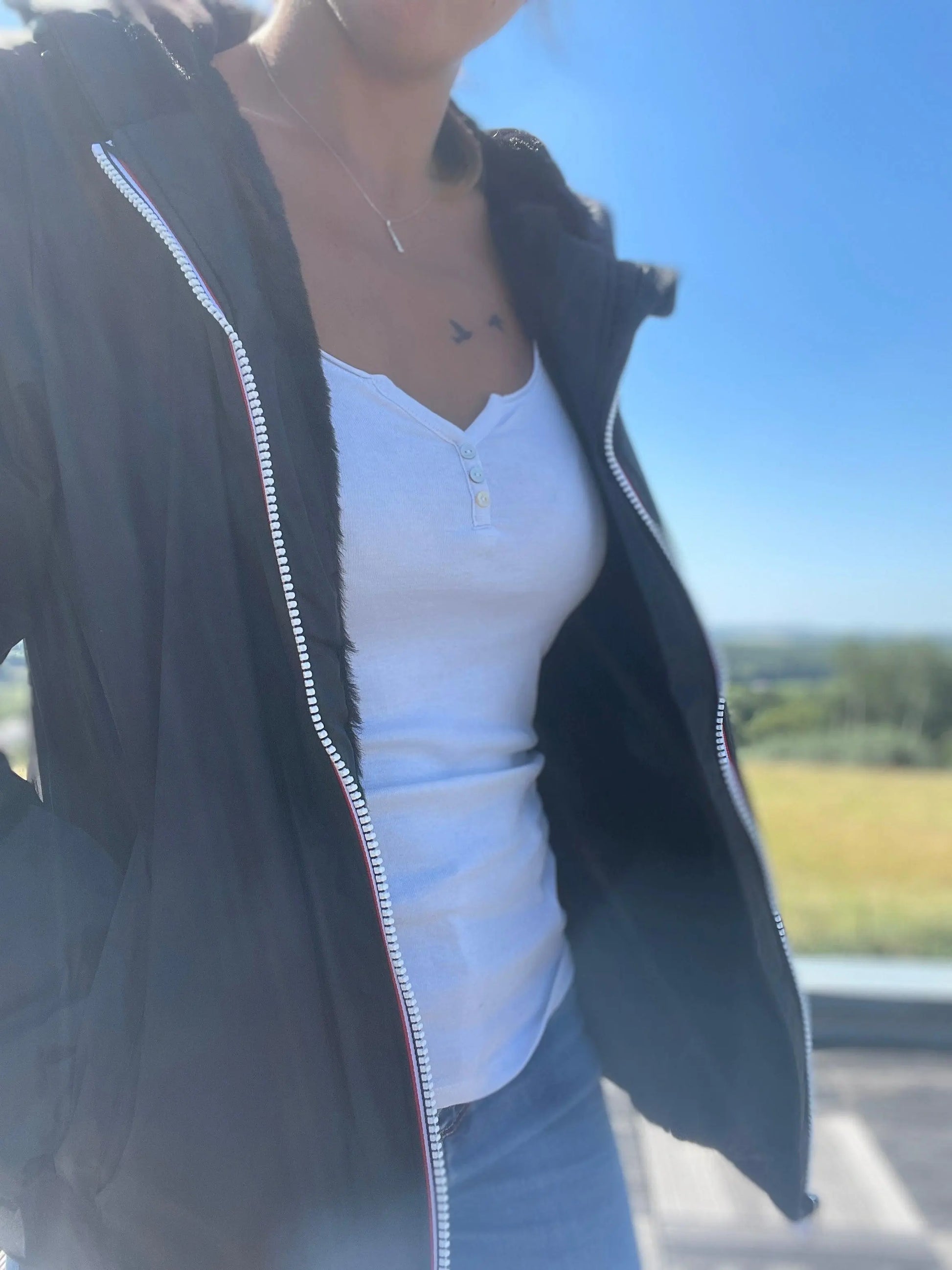 Woman wearing black Laura Jo short waterproof jacket with faux fur lining outdoors