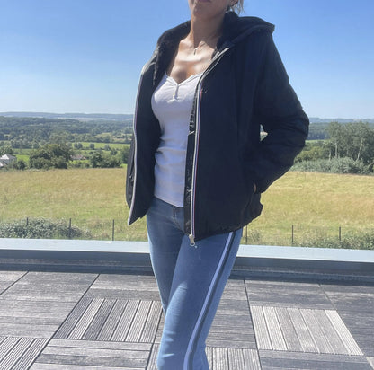 Woman wearing black Laura Jo short waterproof coat and jeans outdoors, Le Petit Placard