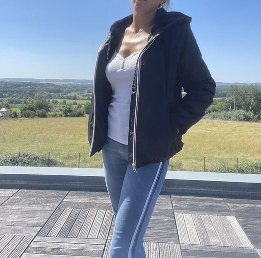 Woman wearing black Laura Jo short waterproof coat and jeans outdoors, Le Petit Placard