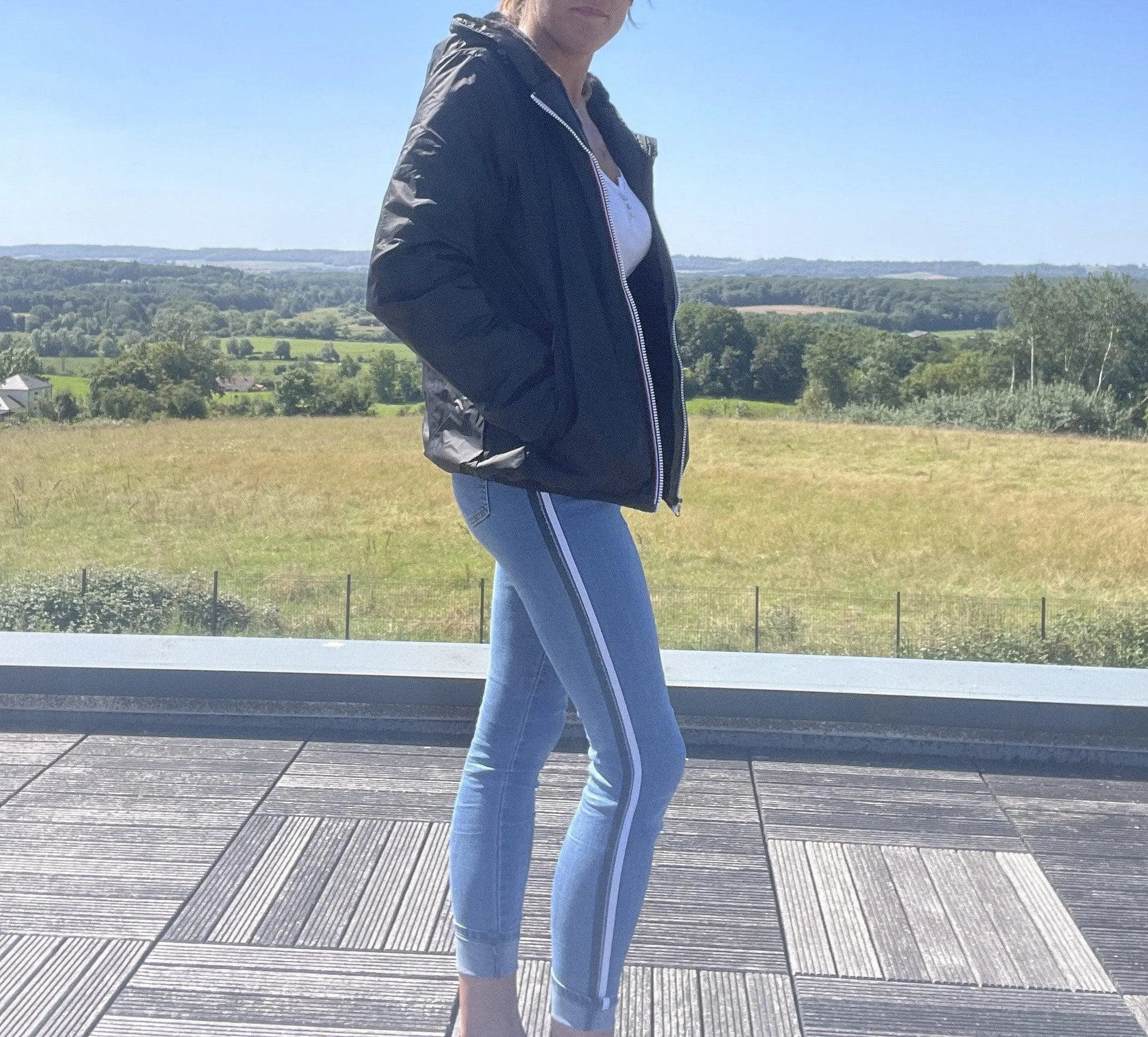 Woman in Laura Jo black rain jacket and striped jeans outdoors, Le Petit Placard fashion