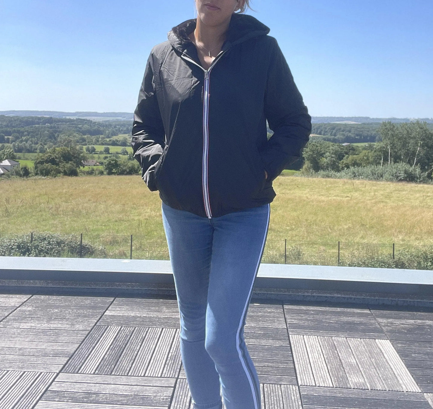 Woman wearing Laura Jo black rain jacket and jeans outdoors, Le Petit Placard style