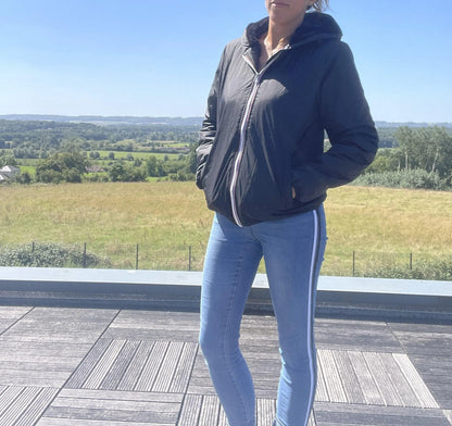 Woman in Laura Jo black waterproof jacket and skinny jeans standing outdoors with scenic view