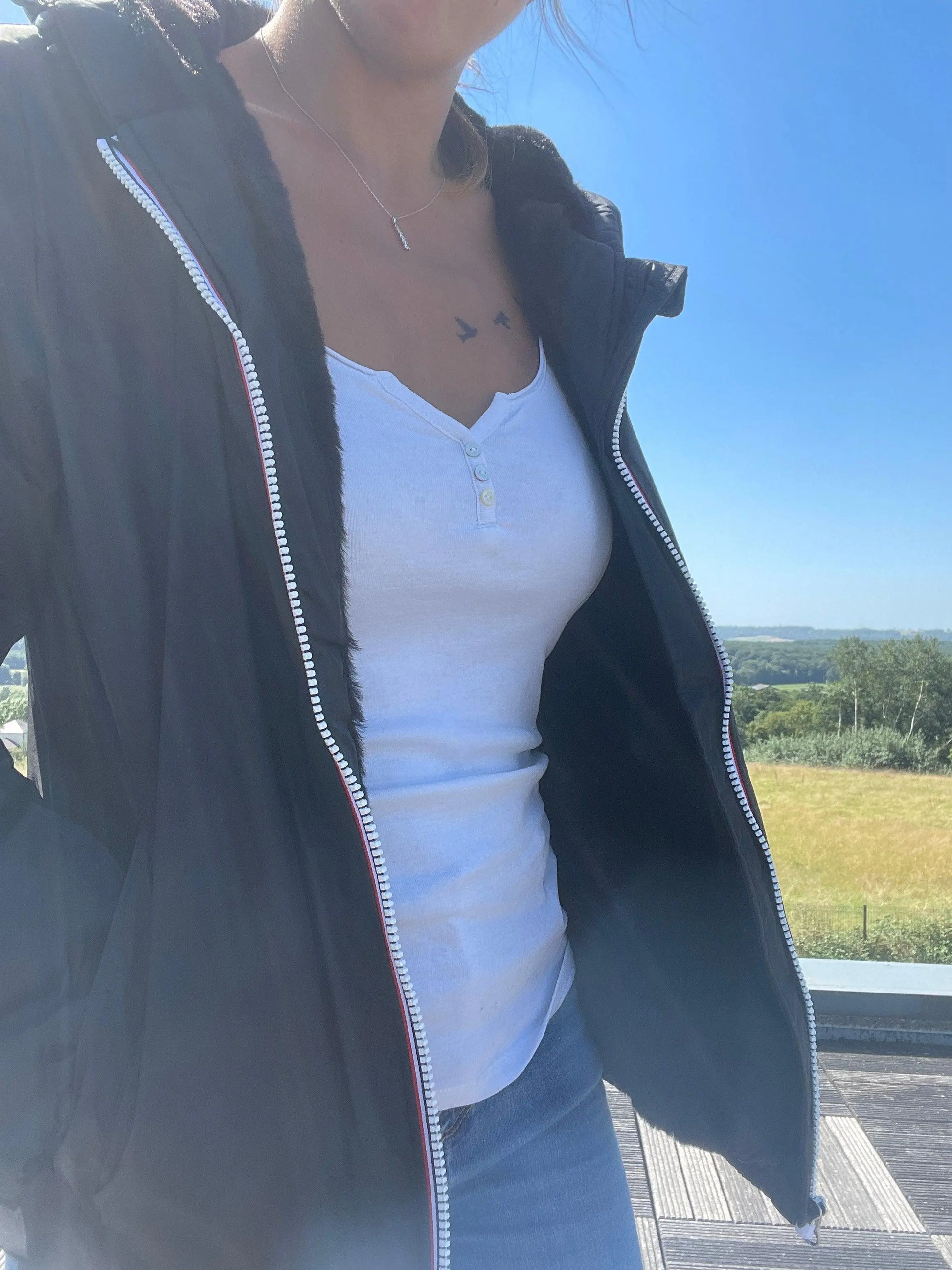Woman wearing Laura Jo raincoat over white top and jeans outdoors, Le Petit Placard