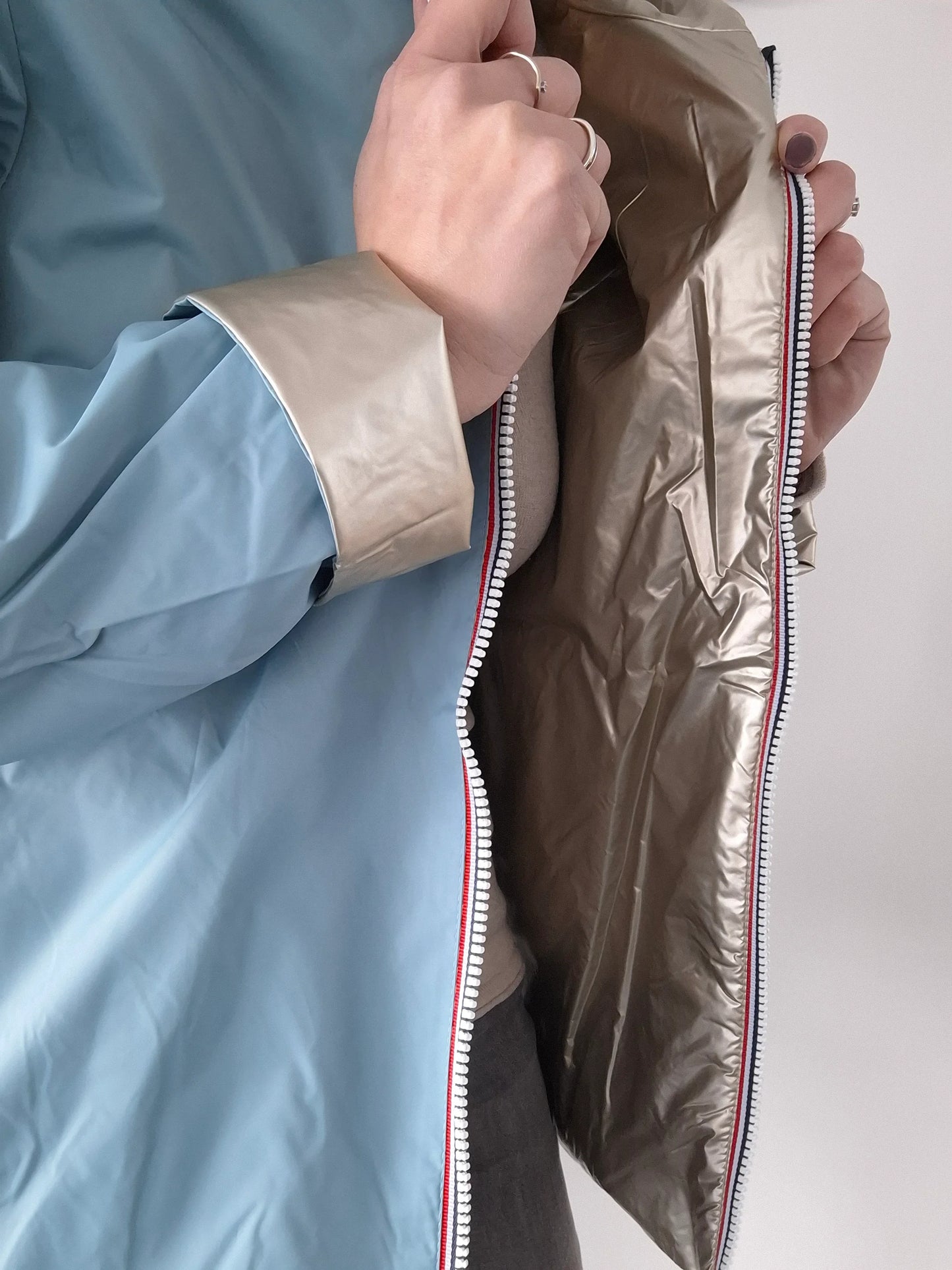 Détail réversible du manteau court bleu ciel et doré Laura Jo, montrant la fermeture éclair tricolore et les deux faces du tissu