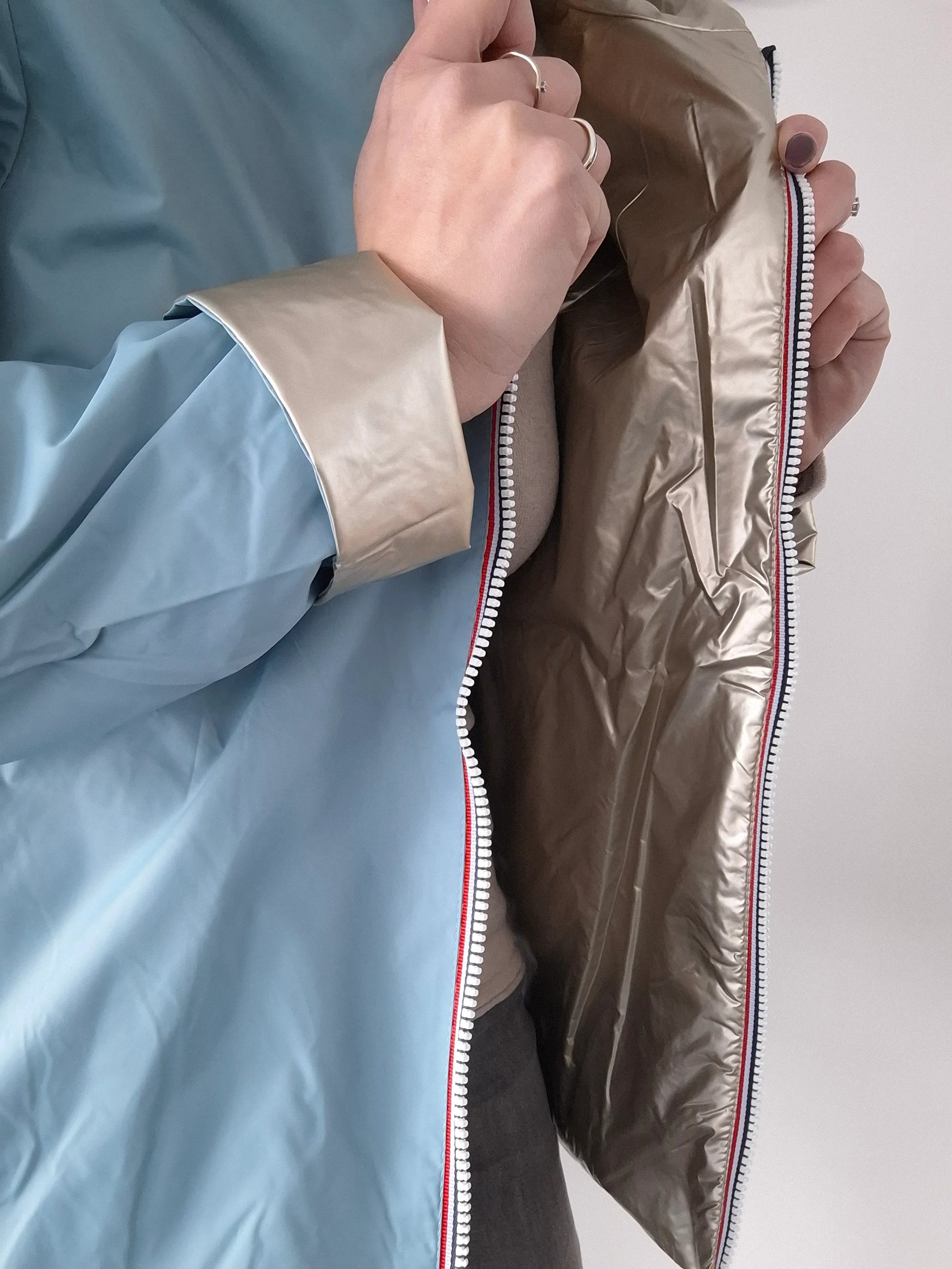 Détail réversible du manteau court bleu ciel et doré Laura Jo, montrant la fermeture éclair tricolore et les deux faces du tissu