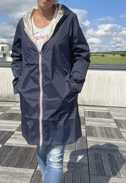 Manteau imperméable réversible Laura Jo, long bleu marine et doré, porté sur mannequin, détails du tissu et design élégant visible.