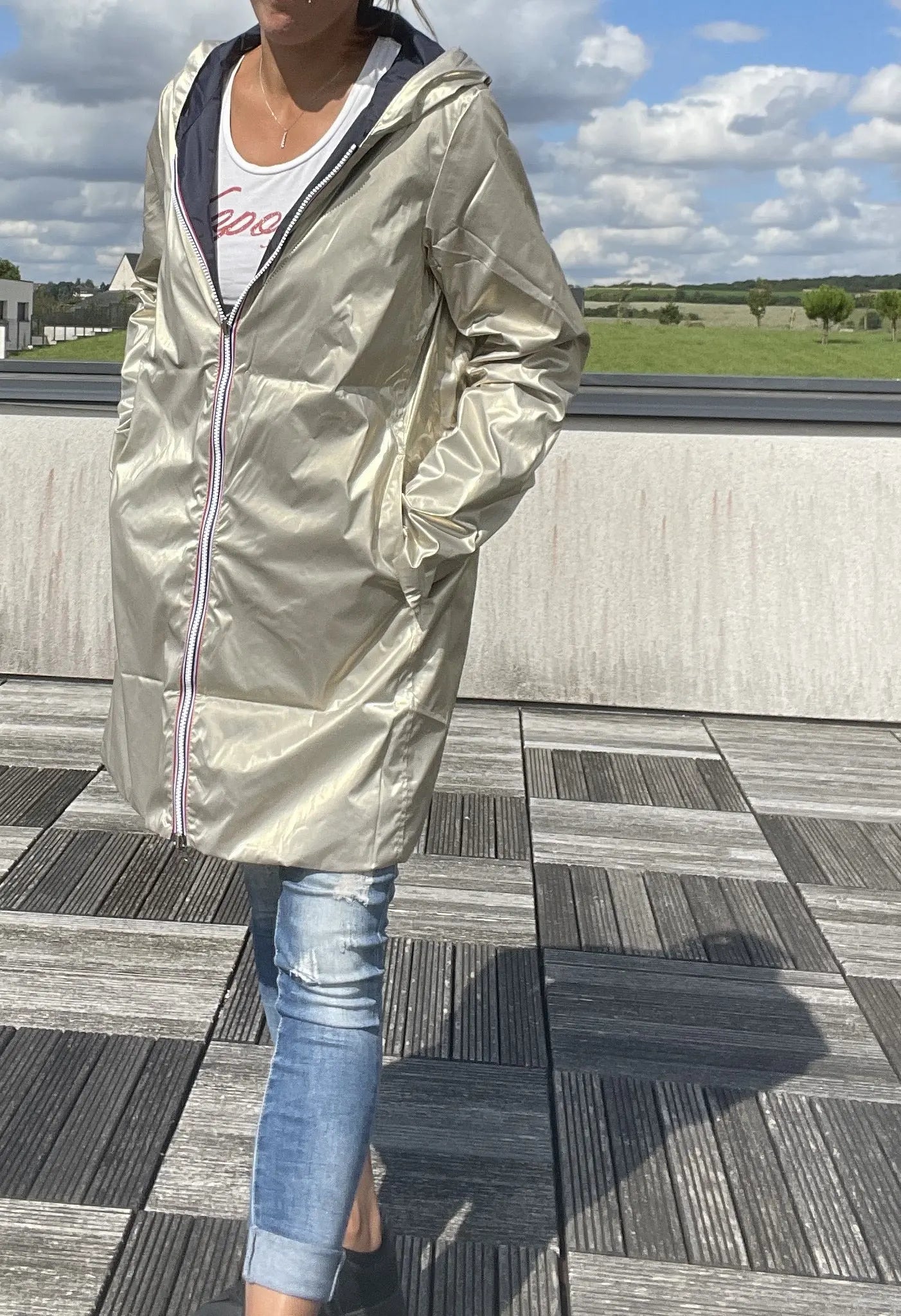 Imperméable réversible long Laura Jo bleu marine et doré, manteau élégant avec capuche, porté en extérieur.