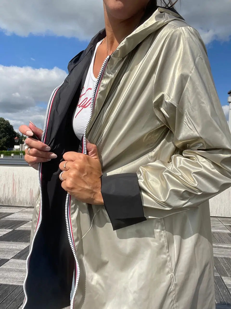 Imperméable réversible long noir et doré Laura Jo avec capuche, sans garnissage, porté sur une mannequin.