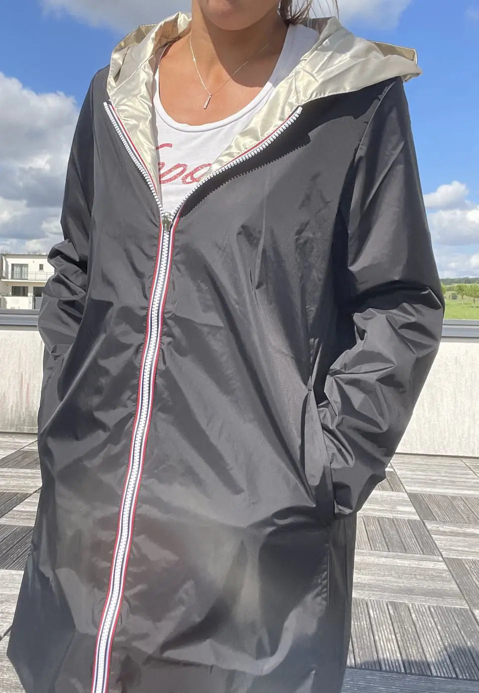 Imperméable réversible long noir et doré Laura Jo avec capuche, sans garnissage, porté en extérieur, style élégant et pratique.