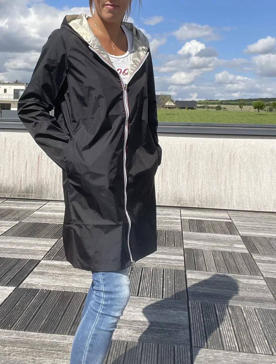 Imperméable réversible long noir et doré Laura Jo avec capuche, sans garnissage, porté par un modèle.