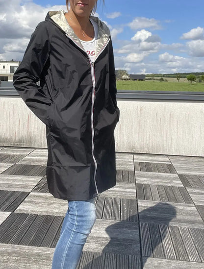 Imperméable réversible long noir et doré Laura Jo avec capuche, sans garnissage, porté par un modèle.