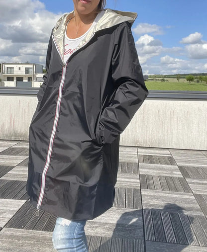 Imperméable réversible long noir et doré Laura Jo avec capuche, sans garnissage, porté en extérieur.