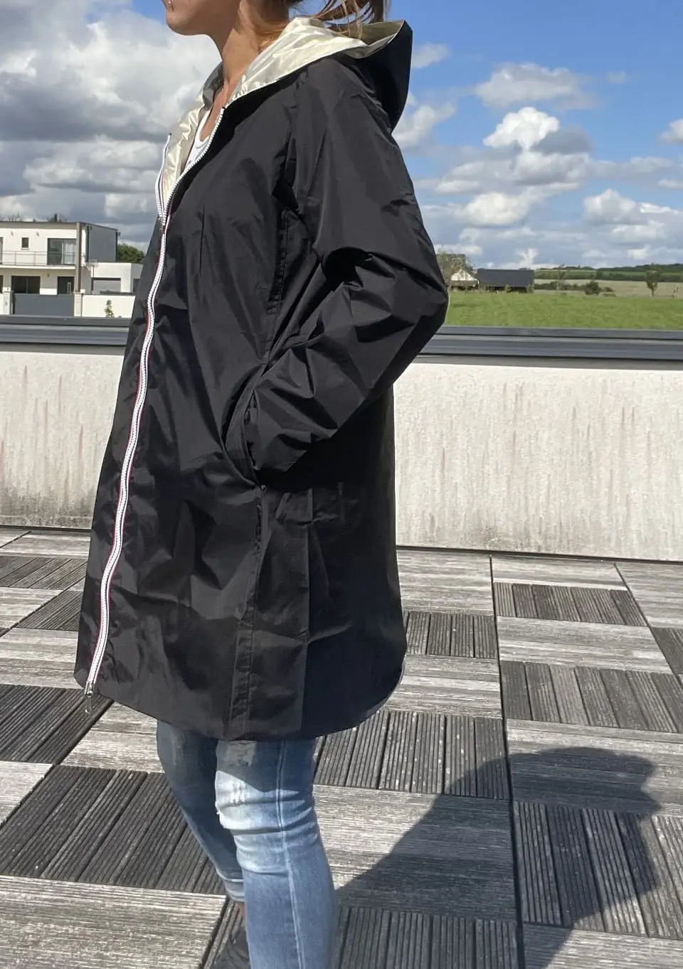 Imperméable réversible long noir et doré Laura Jo avec capuche, sans garnissage, porté par une mannequin.