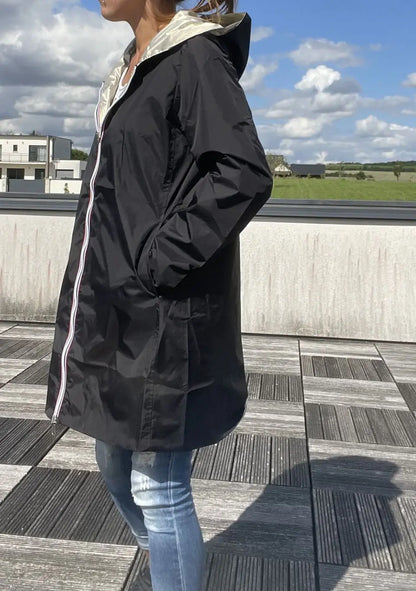 Imperméable réversible long noir et doré Laura Jo avec capuche, sans garnissage, porté par une mannequin.