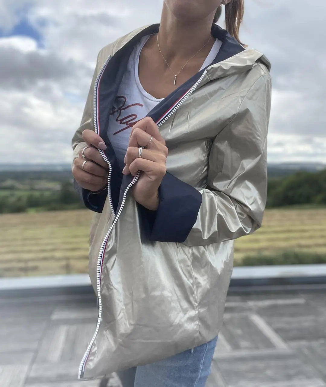 Manteau court imperméable réversible Laura Jo en bleu marine et doré, léger pour la mi-saison, porté en extérieur.
