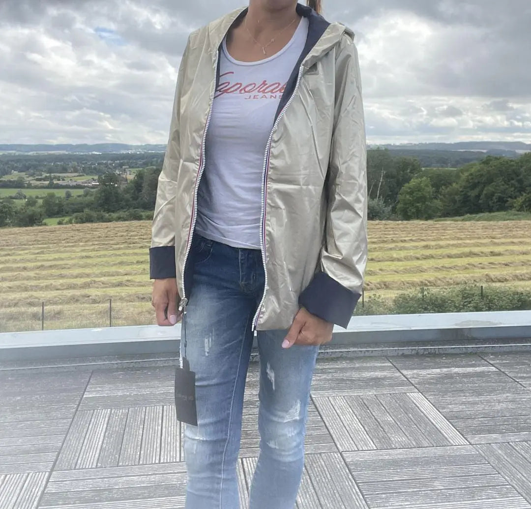 Imperméable réversible Laura Jo court bleu marine et doré, manteau mi-saison léger avec capuche, porté en extérieur.
