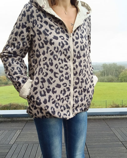 Imperméable réversible court à motif léopard beige et noir, fermeture zippée centrale, manches longues, peu chargé d padding, porté avec jeans.