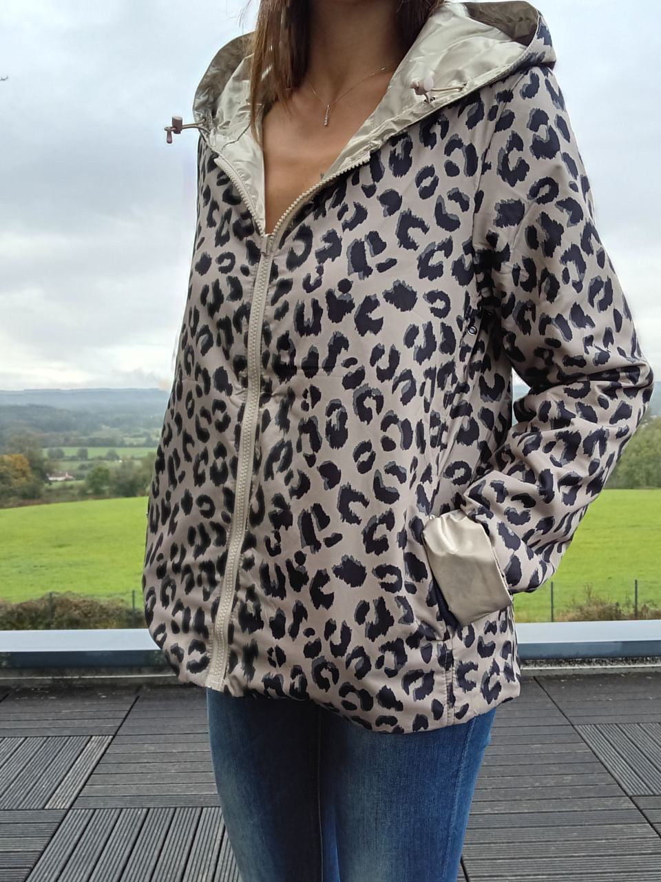 Veste imperméable réversible à motif léopard gris clair et noir, capuche et poches, fermoir zip frontal, garnissage léger.