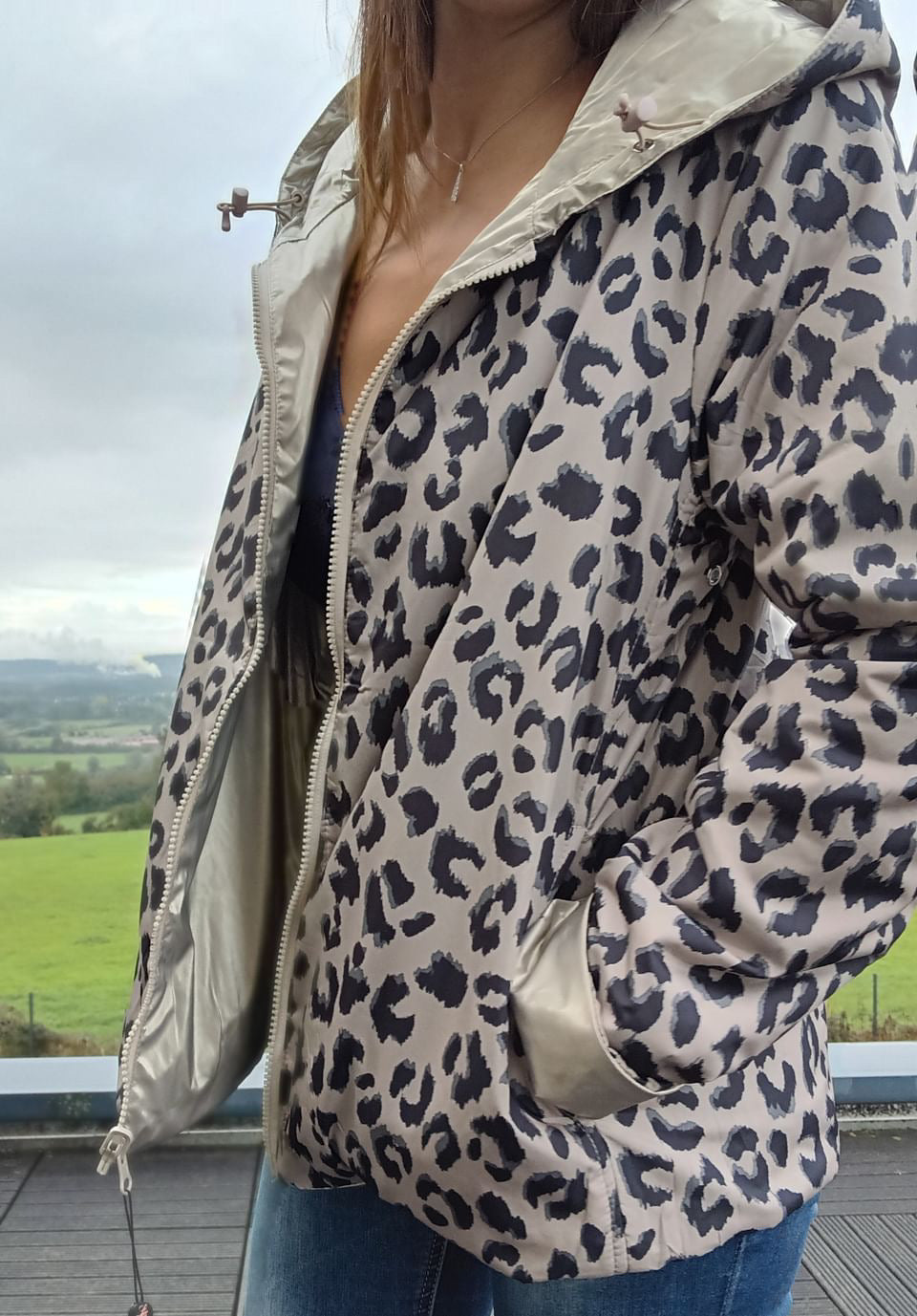 Manteau réversible court à imprimé guépard beige et noir, with zip uni et garnissage en ouate, porté grand ouvert.