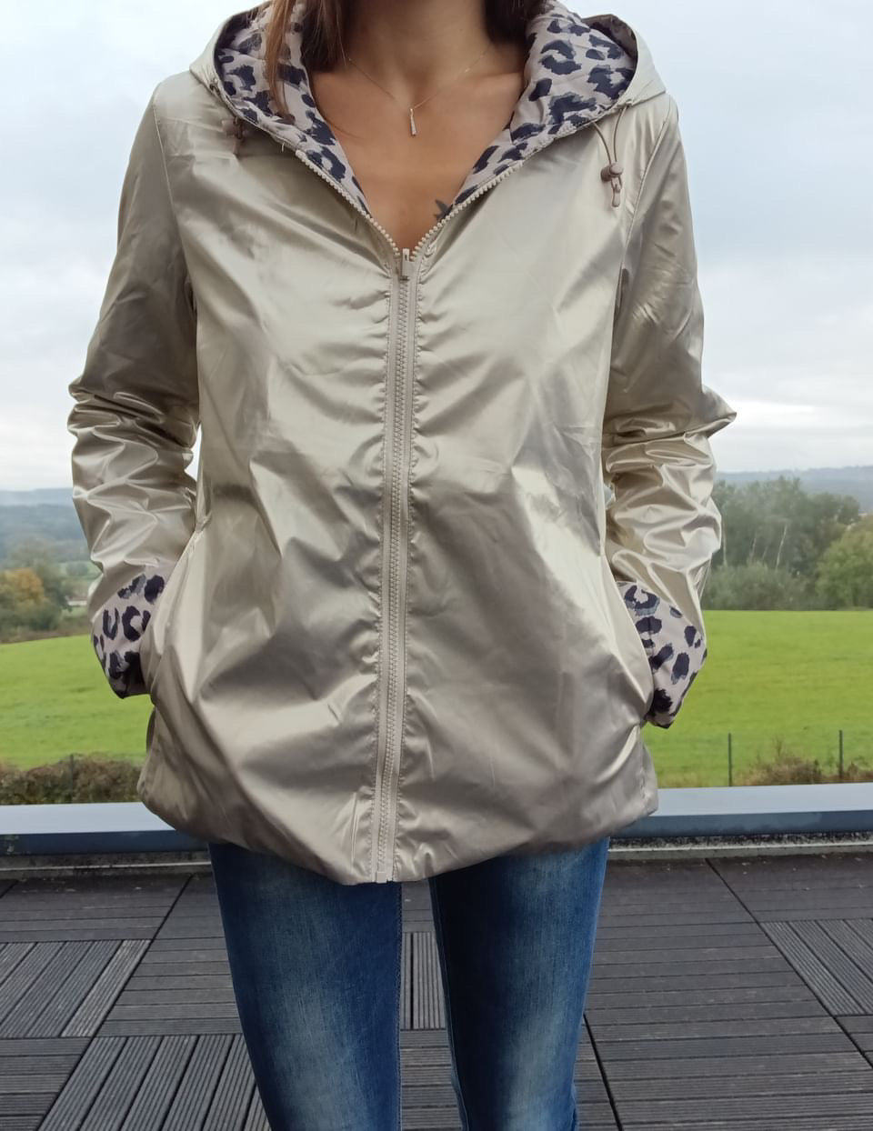 Imperméable réversible couleur beige, zippé au centre, doublure intérieure à motif léopard gris et noir; poches côtés, capuche assortie et ourlet légèrement évasé.