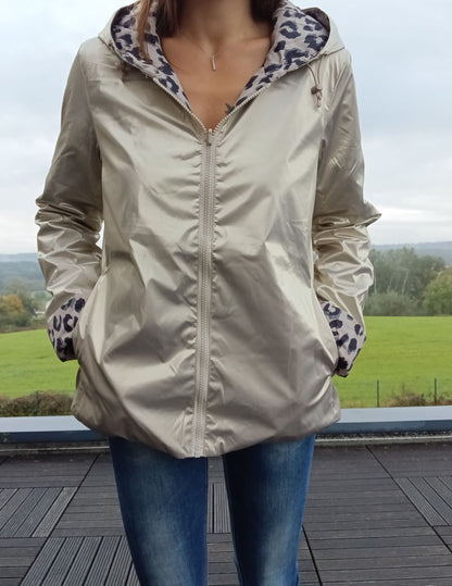 Imperméable réversible couleur beige, zippé au centre, doublure intérieure à motif léopard gris et noir; poches côtés, capuche assortie et ourlet légèrement évasé.