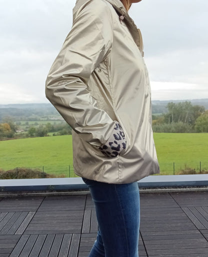 Imperméable réversible court couleur doré avec garnissage mi-saison; manchon droit et poches, vue côté d’une femme sur terrasse.
