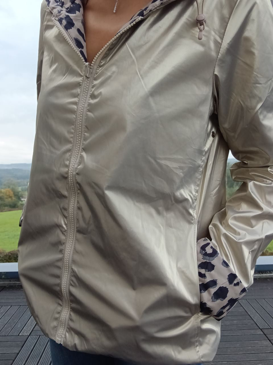 Imperméable réversible court couleur beige avec capuche zippée, ouverture sur le devant et poches; léger garnissage mi-saison, doublure imprimée léopard visible sur les manches.