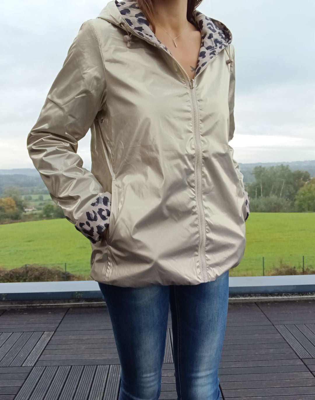 Imperméable court beige réversible avec doublure léopard, fermeture zip centrale et poches, porté avec jeans. Laura Jo - Curvy.