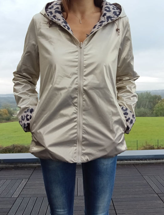 Imperméable réversible beige court, garnissage ouate, ouverture zippée centrale, doublure léopard gris sur la capuche et les manches, porté avec jean.