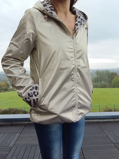 Imperméable réversible beige avec capuche, zippé devant, doublure à motif léopard sur l’intérieur et sur les manches; porté en extérieur.