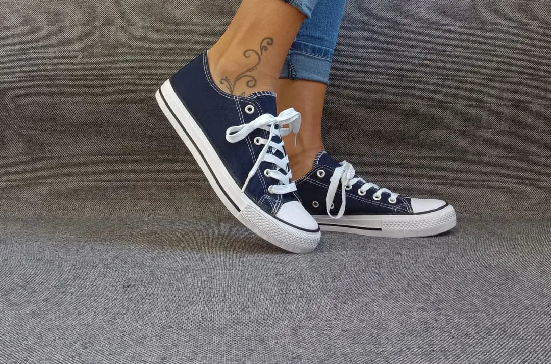 Baskets basses bleu marine et blanc type converse portées par une femme en jean, lacets blancs et semelle blanche