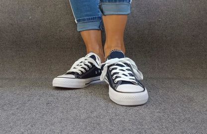 Baskets basses bleu marine et blanc type converse portées avec un jean, semelle blanche et lacets blancs