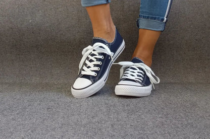 Baskets basses bleu marine et blanc type converse portées avec un jean, lacets blancs et semelle blanche