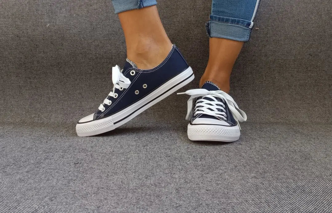 Baskets basses bleu marine et blanc type converse portées avec un jean, semelle blanche et lacets blancs