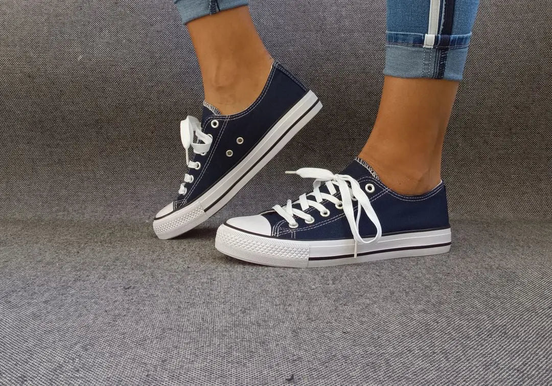 Baskets basses bleu marine et blanc type converse portées avec un jean, semelle blanche et lacets blancs
