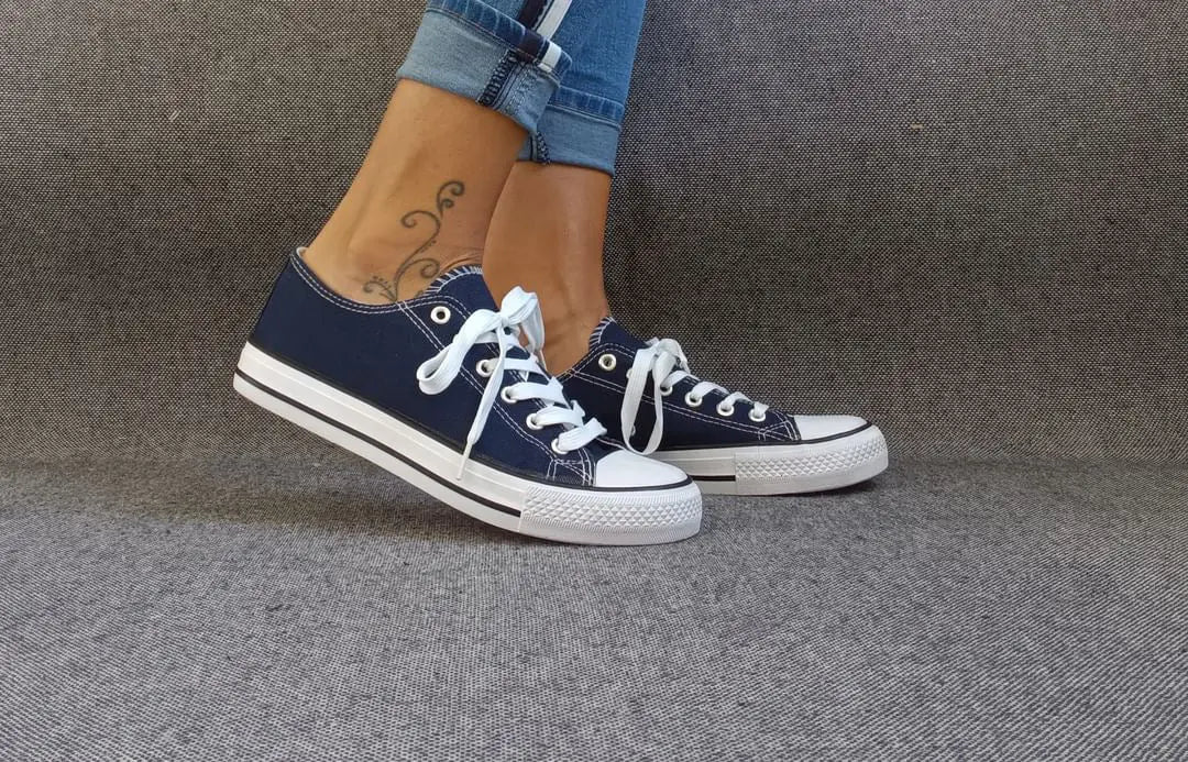 Baskets basses bleu marine et blanc type converse portées avec un jean, lacets blancs et semelle blanche