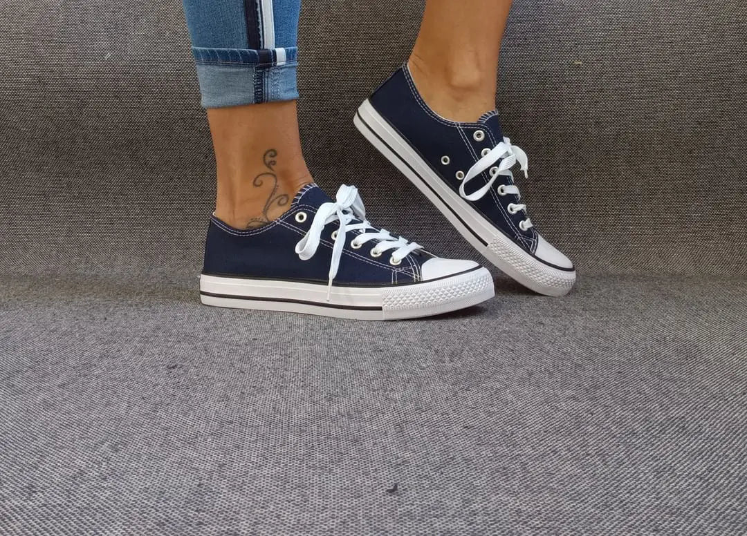 Baskets basses bleu marine et blanc type converse portées avec un jean, lacets blancs et semelle blanche