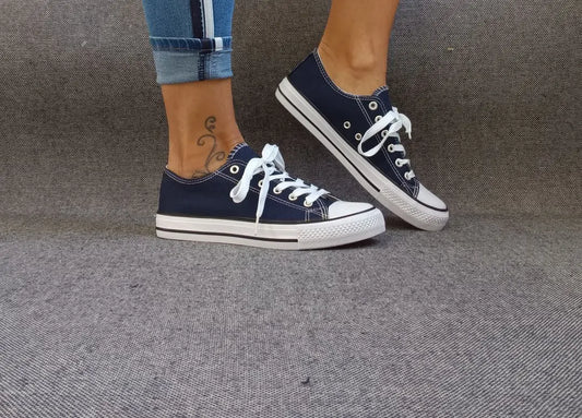 Baskets basses bleu marine et blanc type converse portées avec un jean, lacets blancs et semelle blanche