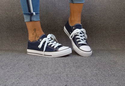 Baskets basses bleu marine et blanc type converse portées avec un jean, lacets blancs et semelle blanche